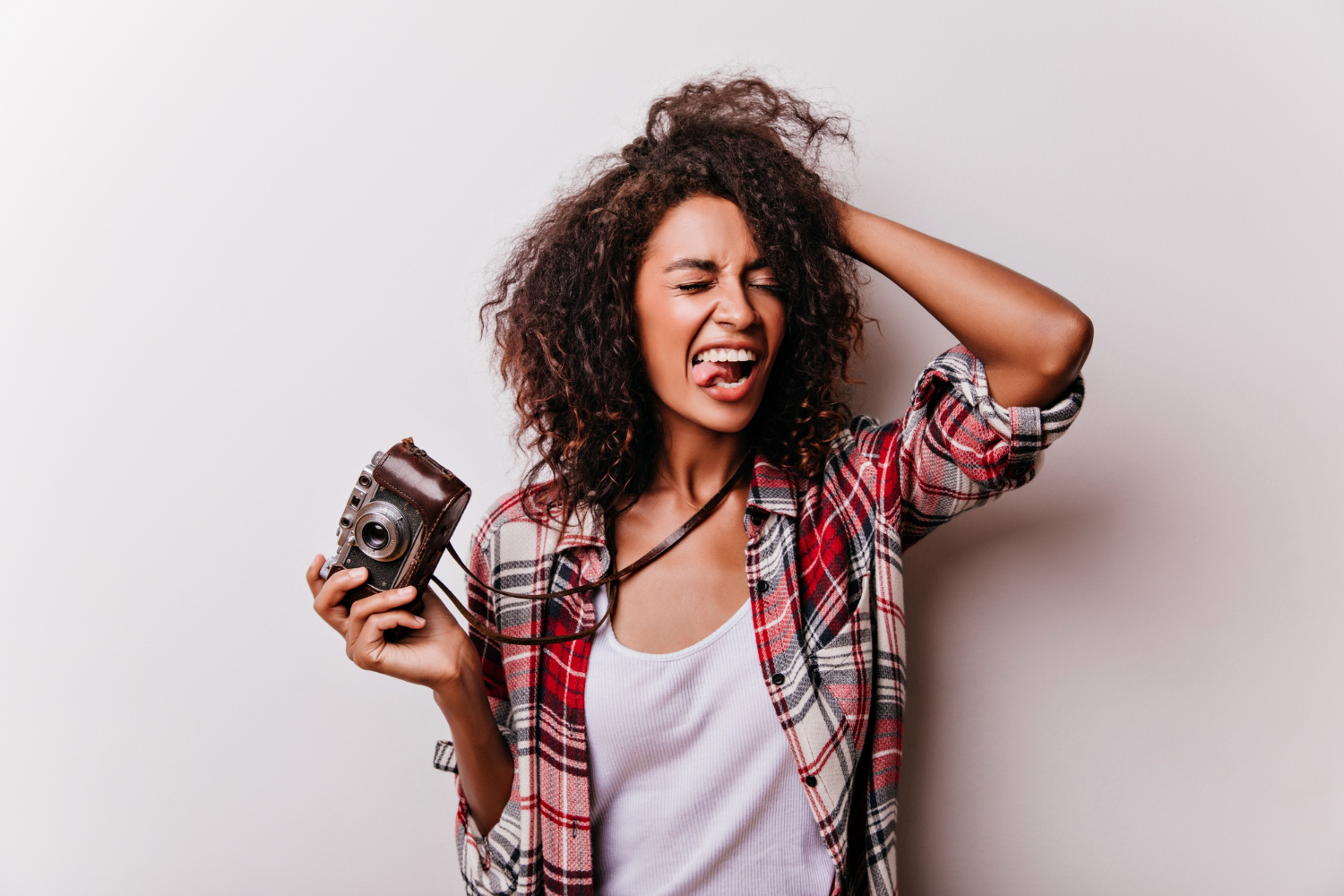 Mulher sorridente segurando uma câmera fotográfica vintage, representando atividades para substituir o celular com hobbies criativos e descontraídos.