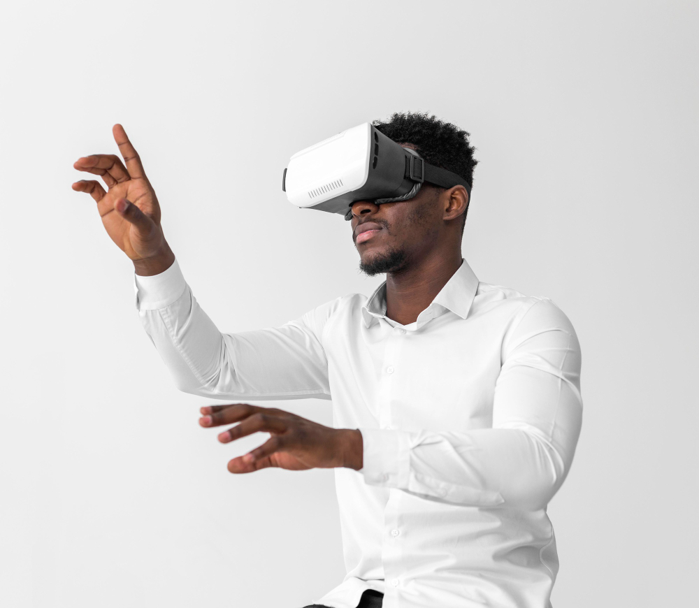 homem negro vestido de camisa branca, usando um óculos de realidade virtual e fazendo movimento com as mãos
